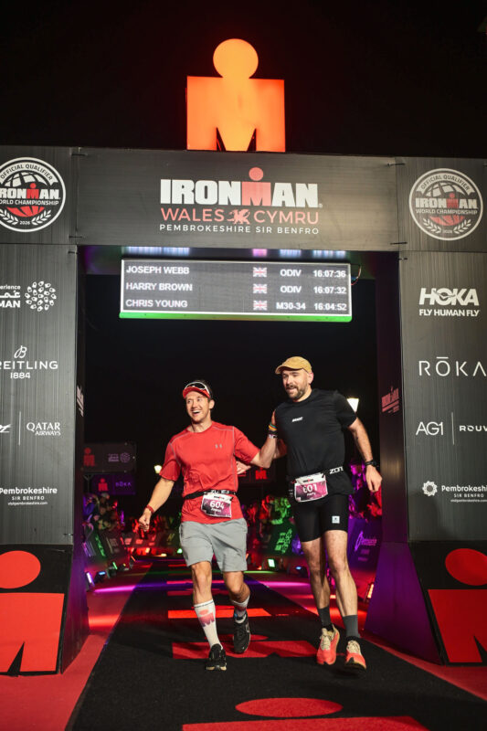 Harry Brown and Joseph Webb crossing the Ironman Wales finish line together