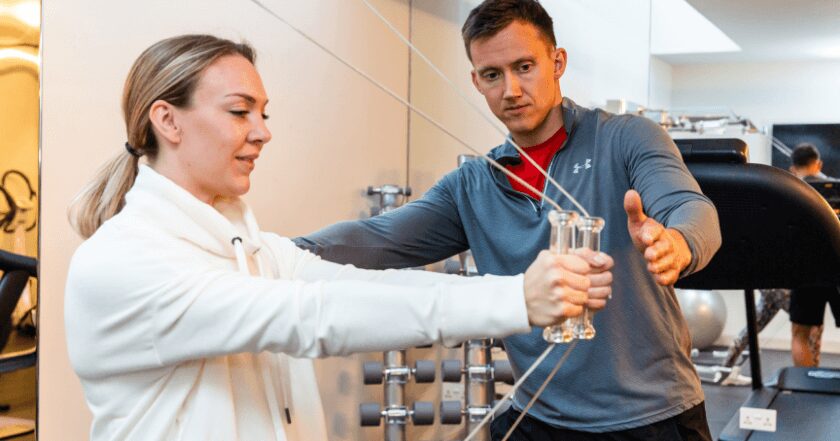 Joseph Webb coaching a client through a cable exercise