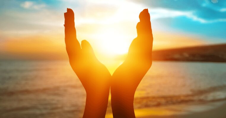 Hands raised towards the sun over the sea